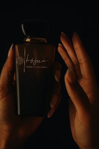 Dark brown perfume bottle with 'kosui' branding held by a hand against a black background